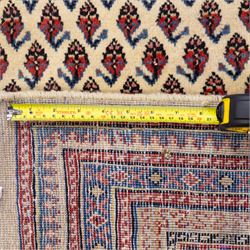 North West Persian Boteh-Mir hand-knotted rug, madder red field decorated with an all-over lattice of small boteh motifs and a central stepped lozenge medallion with repeating stylized boteh and geometric devices, spandrels similarly worked, with multiple narrow borders of floral and geometric bands, in tones of madder red, indigo blue, ivory, and soft green, with cotton fringe ends