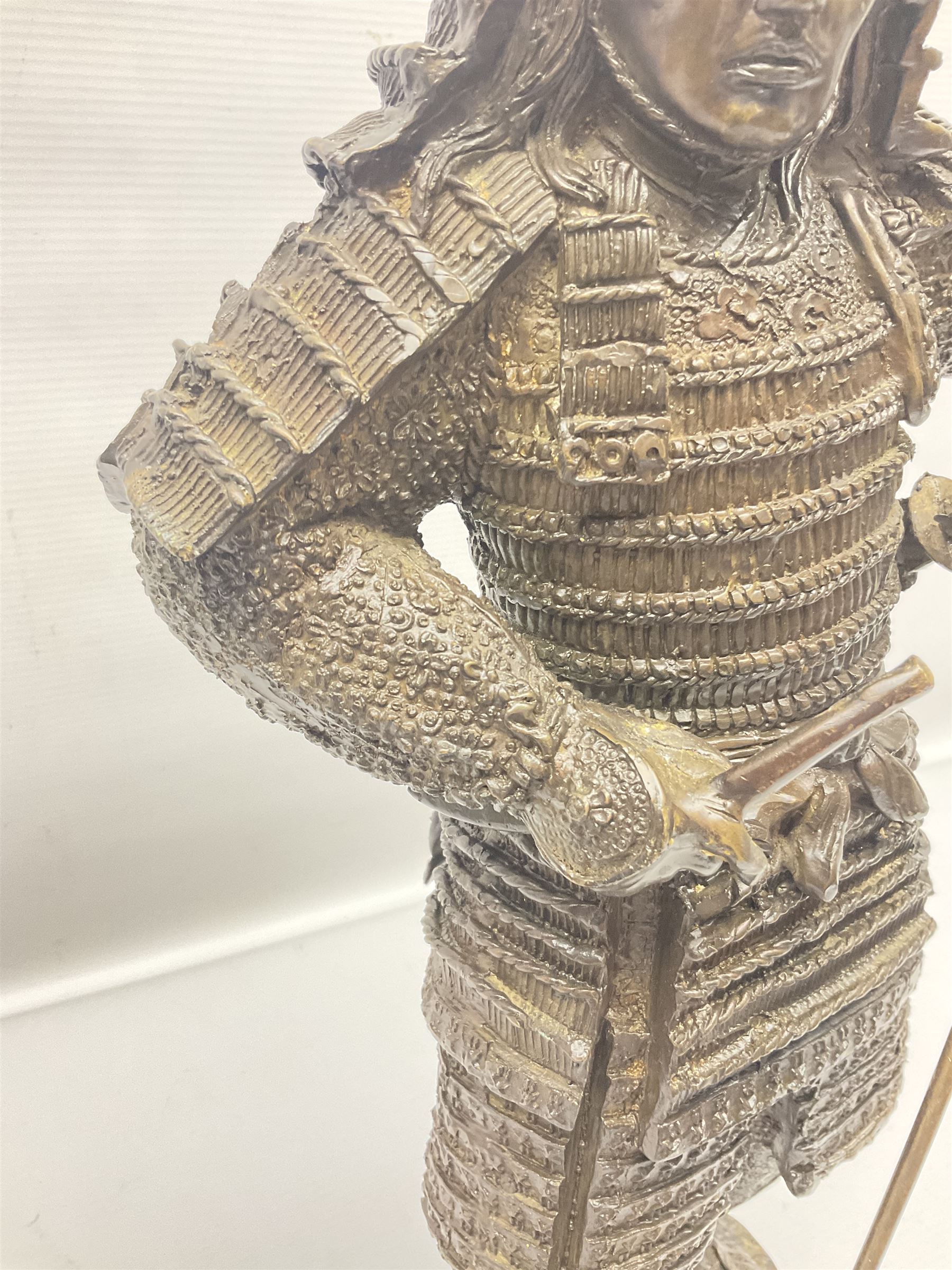 Bronze figure of a samurai standing wearing armour and holding a naginata, upon a rocky base, H48cm