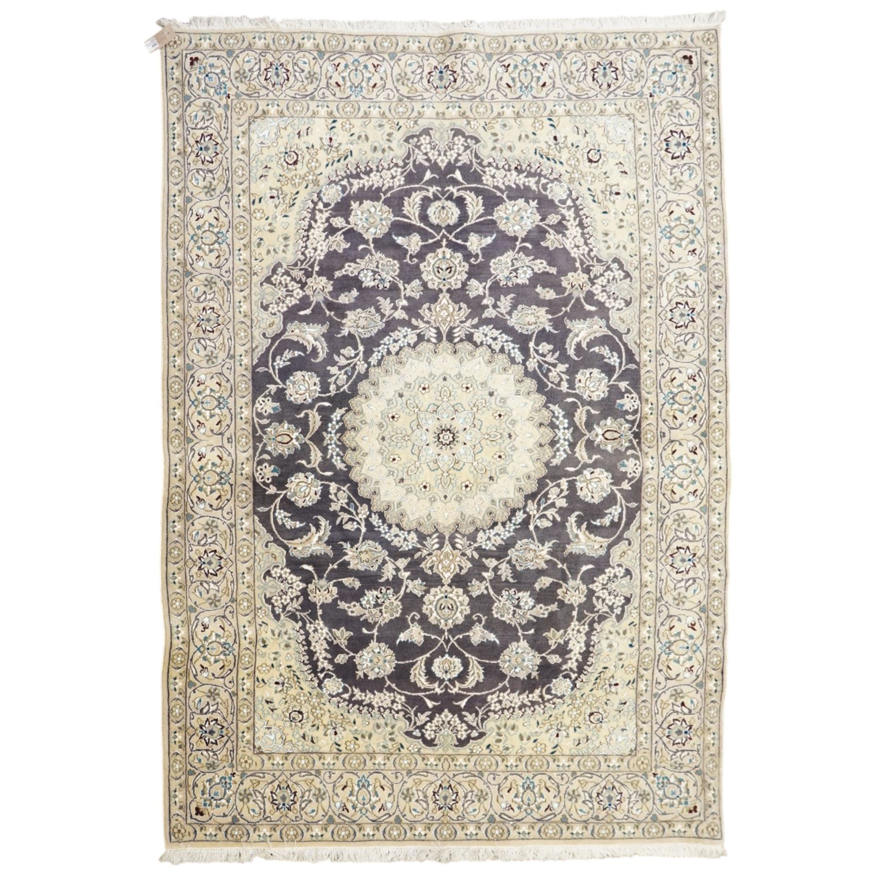 Central Persian Nain hand-knotted carpet, indigo field with central cusped medallion of radiating palmette form, enclosed with an elongated cartouche issuing network of scrolling vine work, arabesques and flowering sprays, surrounding ivory field of conforming design filled with foliate motifs and palmettes, spandrels of complimentary design with angular reserves, within principal border of ivory ground with scrolling vinery rosettes and arabesques, flanked by narrow guard stripes, with cotton fringe ends 