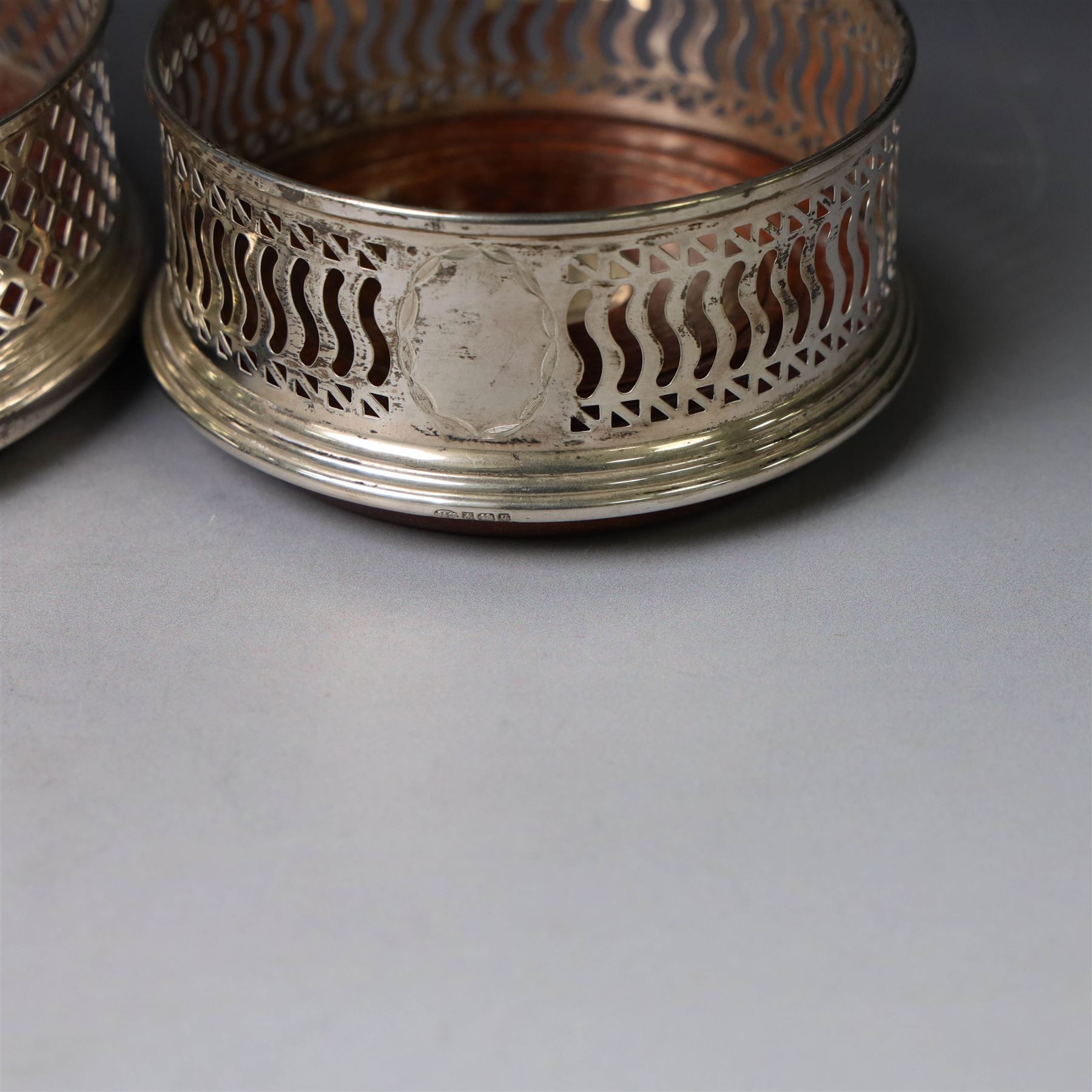 Two silver mounted bottle coasters, the larger example with latticework sides, hallmarked Mappin & Webb Ltd, Birmingham 1993, the smaller example with pierced sides, hallmarked W I Broadway & Co, Birmingham 1998, largest D12cm