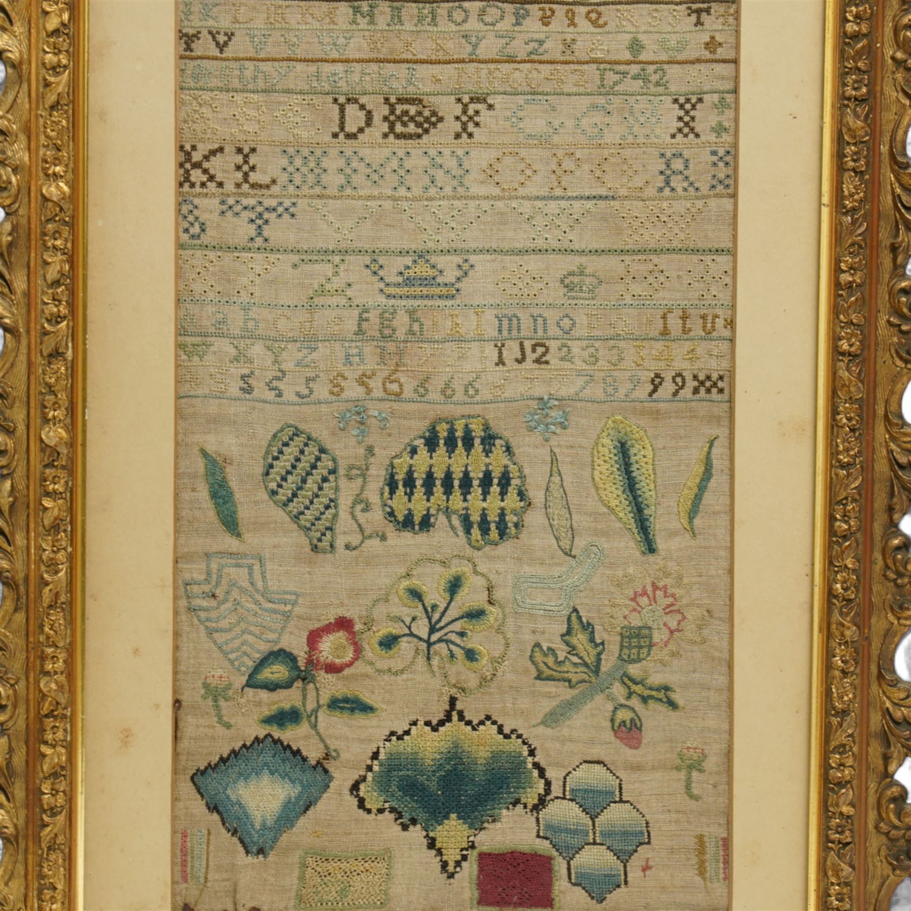George II sampler, Dorothy Dethick, dated 1742, worked with bands of the alphabet, the lower section finely worked with various floral and foliate motifs, most likely examples of her practicing her technique, contained within ornately carved gilt frame 37.5cm x 21cm 