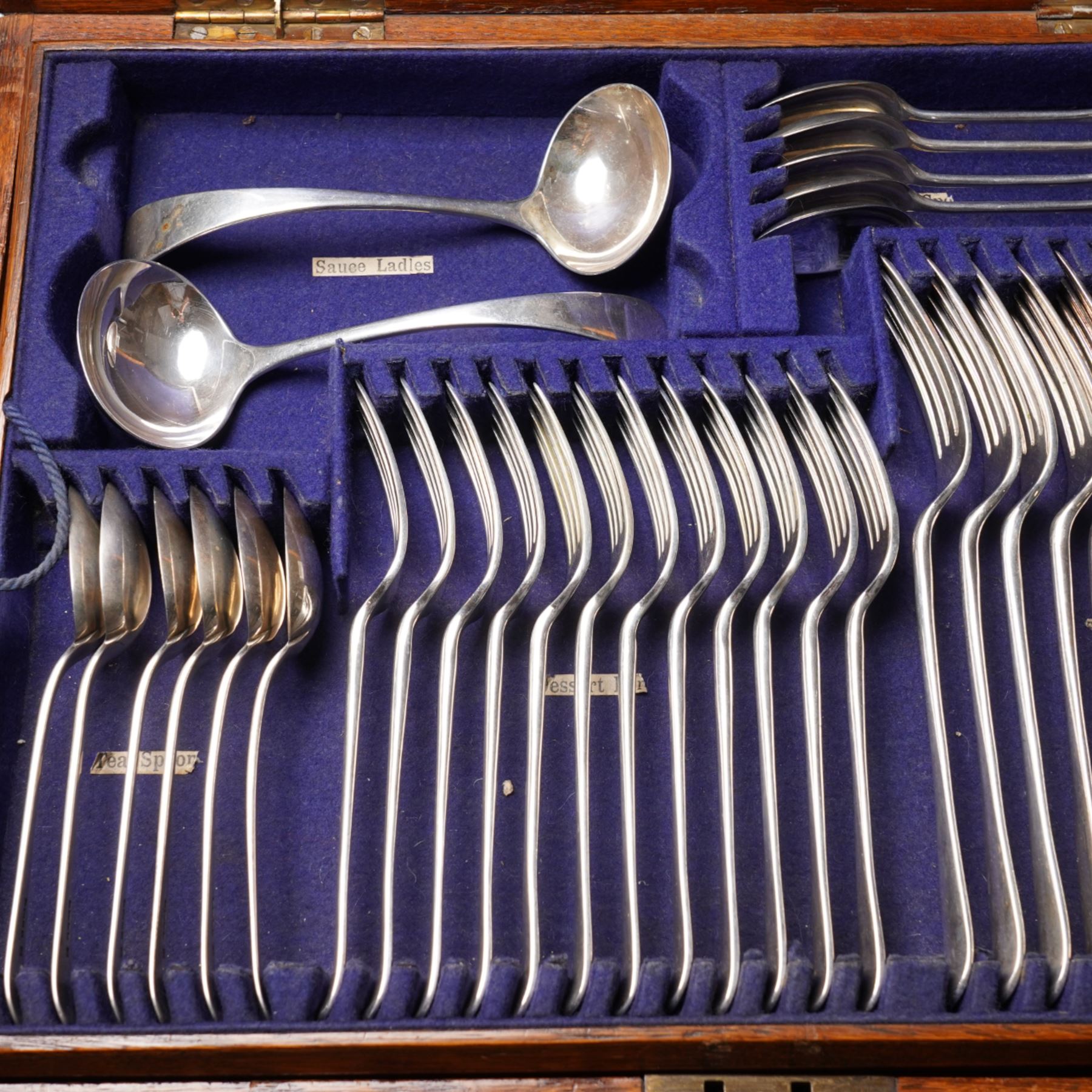 Canteen of Edwardian silver Old English pattern cutlery for twelve covers comprising twelve table forks, twelve dessert forks, twelve soup spoons, twelve dessert spoons, eleven tea spoons, pair of sauce ladles, four table spoons and a basting spoon in oak case London 1907 Maker Charles Boyton & Son