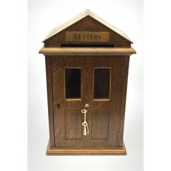 Edwardian oak domestic post box modelled as a sentry box, the pitched roof with brass inset panel to the front gable inscribed Letters, hinged door below with twin glass panes above panels, H39cm x W23cm 
