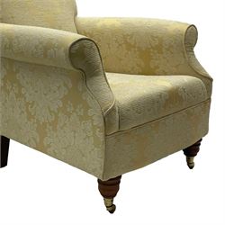 Traditionally shaped hardwood-framed armchair, rolled back and arms, upholstered in pale gold and cream damask fabric with repeating foliate pattern, on turned feet with brass cups and castors