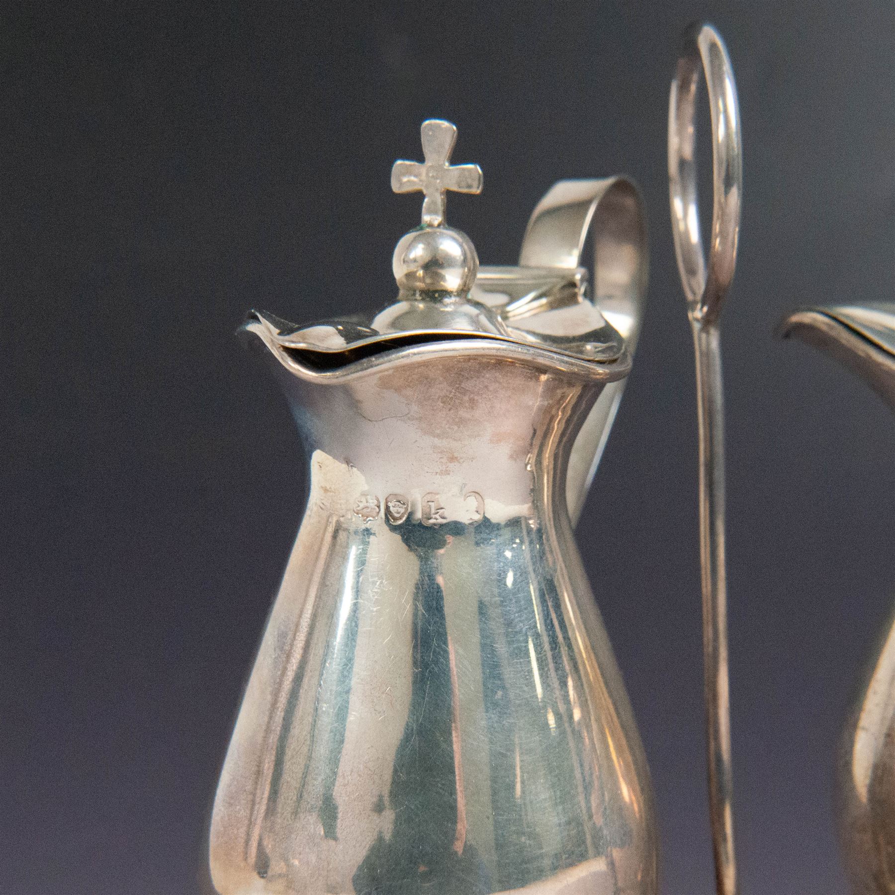 Ecclesiastical silver cruets, comprising two jugs in the form of miniature wine carafes, one hallmarked London 1825, the other unmarked, contained in a silver cruet stand with loop handle, hallmarked London 1937, and a French silver jar and cover in the form of a miniature chalice, with Minerva's head standard mark, tallest H13cm