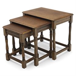 Nest of three dark oak tables, rectangular top with turned supports, tables suspended on rails