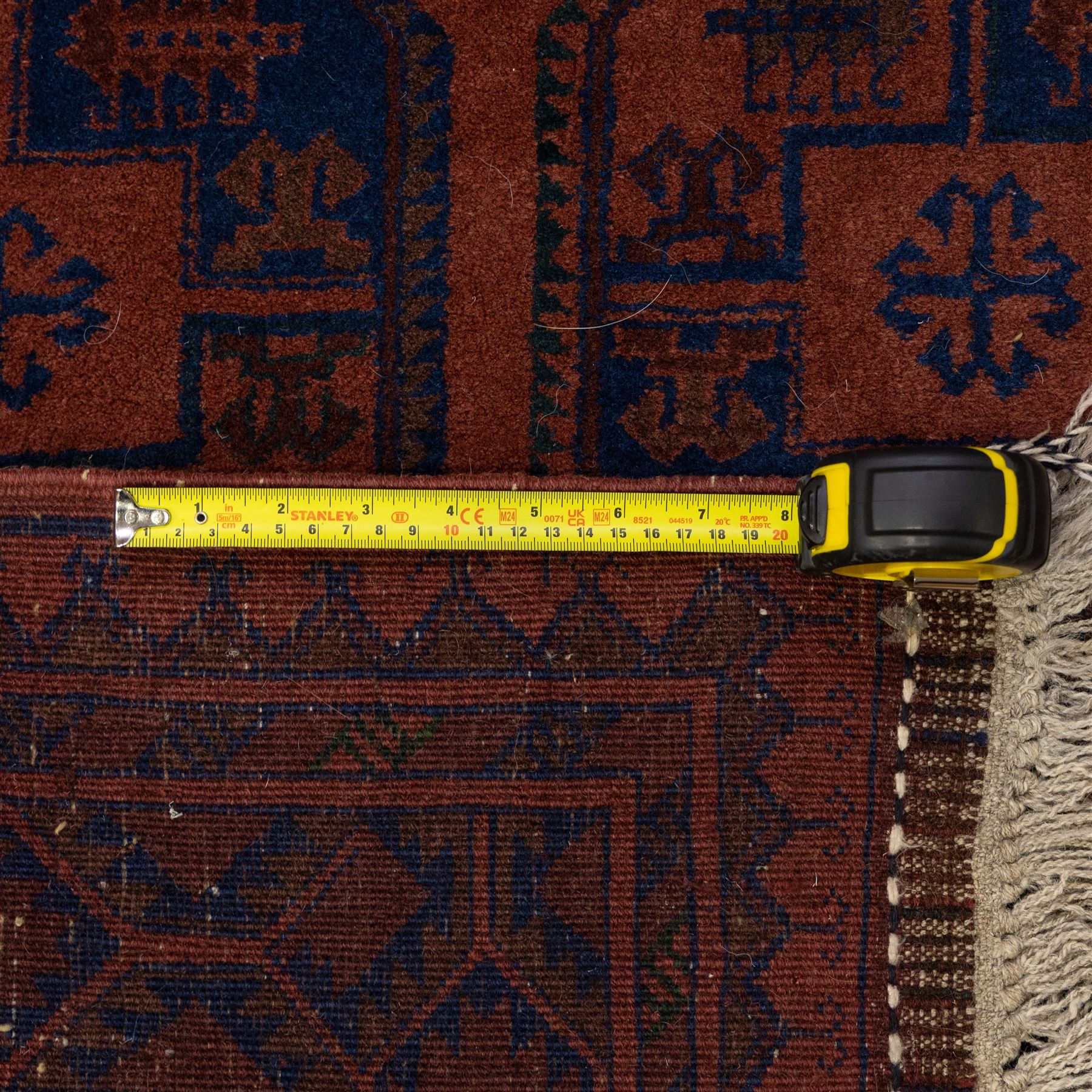 South East Persian Afshar hand-knotted rug, red ground decorated with a geometric design of octagonal medallions and incorporating stylized motifs in tones of indigo and dark brown within geometric borders, with fringe ends  