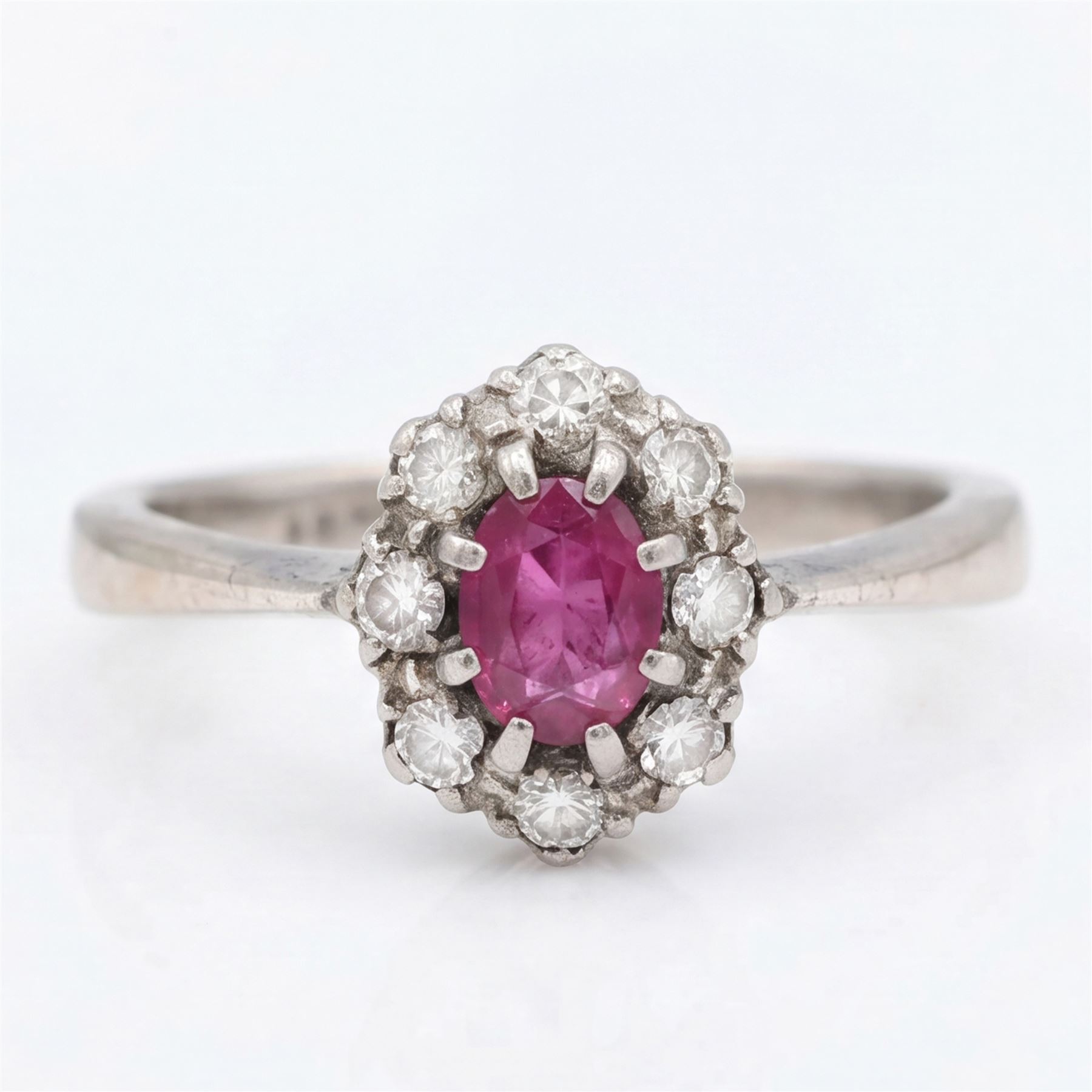 White gold ruby and diamond cluster ring, single oval cut ruby of approx 0.45 carat, surrounded by eight single cut diamonds, stamped 18ct, total diamond weight approx 0.15 carat