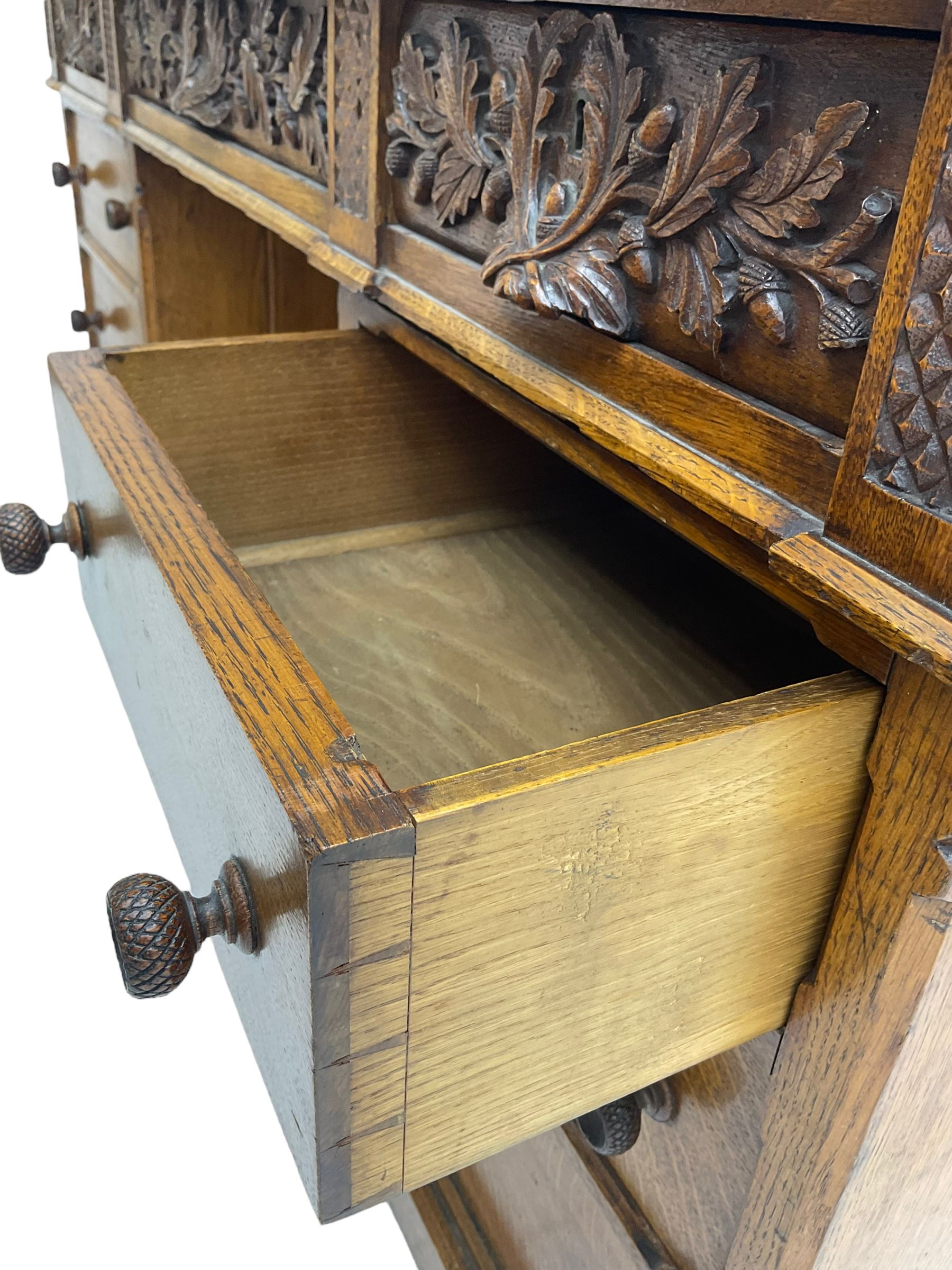 Late 19th century heavily carved oak twin pedestal desk, rectangular top with two raised trinket or correspondence structures each with three drawers, rectangular top over three frieze drawers carved with acorn and oak leaf decoration, each pedestal with three drawers with acorn husk shaped handles