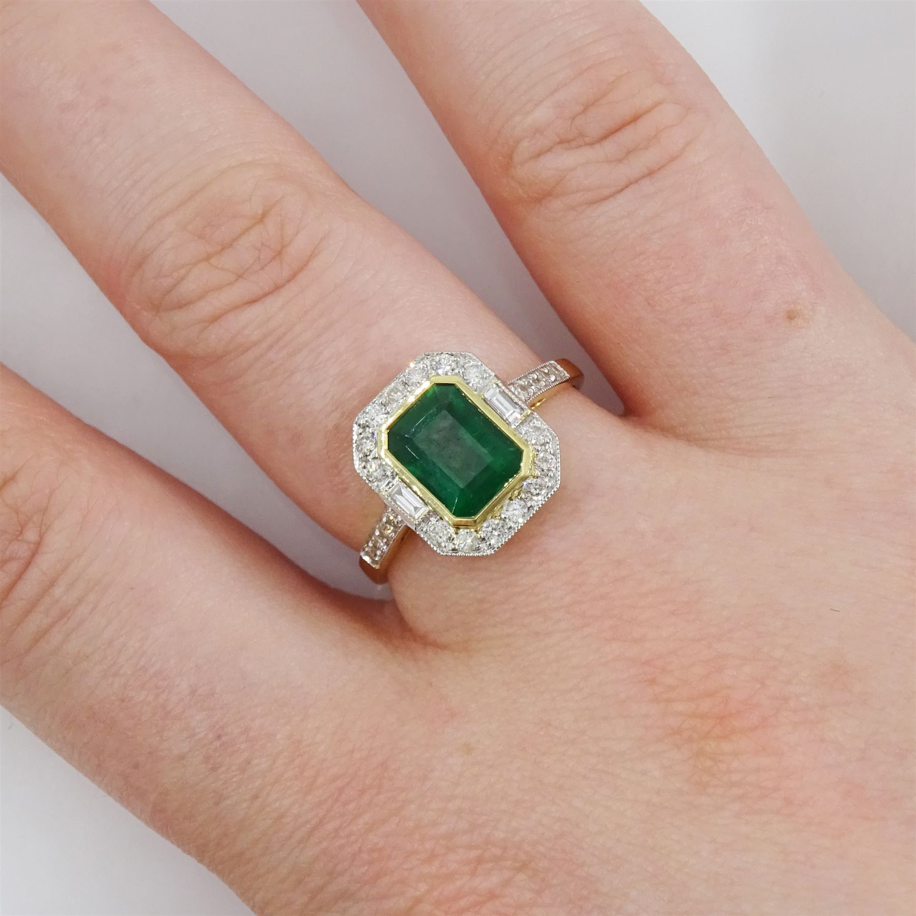 18ct gold emerald and diamond cluster ring, octagonal cut emerald of approx 1.50 carat, with milgrain set, round brilliant and baguette cut diamond surround and diamond set shoulders, stamped 750, total diamond weight approx 0.45 carat