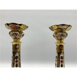 Mid 20th century Royal Crown Derby Old Imari 1128 pattern candlesticks, each with shaped drip tray affixed to squat socket, upon spreading stem and canted square base with gilt dolphin edges, with printed marks beneath including Roman numeral year cypher for 1968, H26.5cm