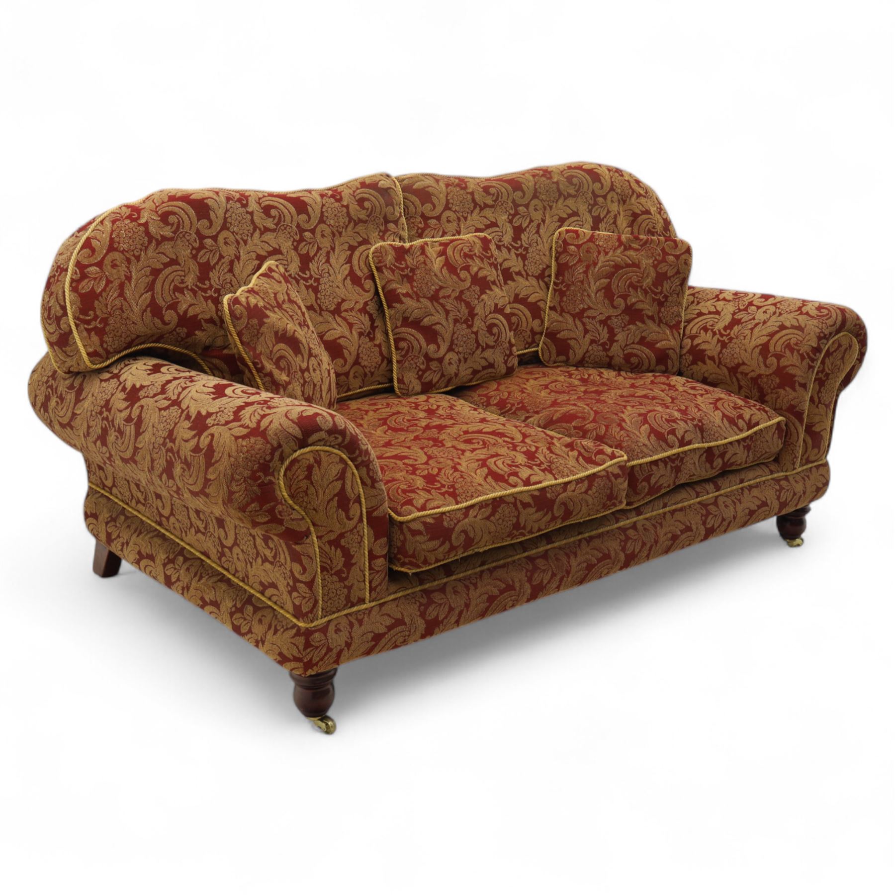Duresta - two seat settee, upholstered in red and gold damask fabric with piped edges, scroll arms and loose feather-filled cushions, raised on turned wooden feet with brass castors