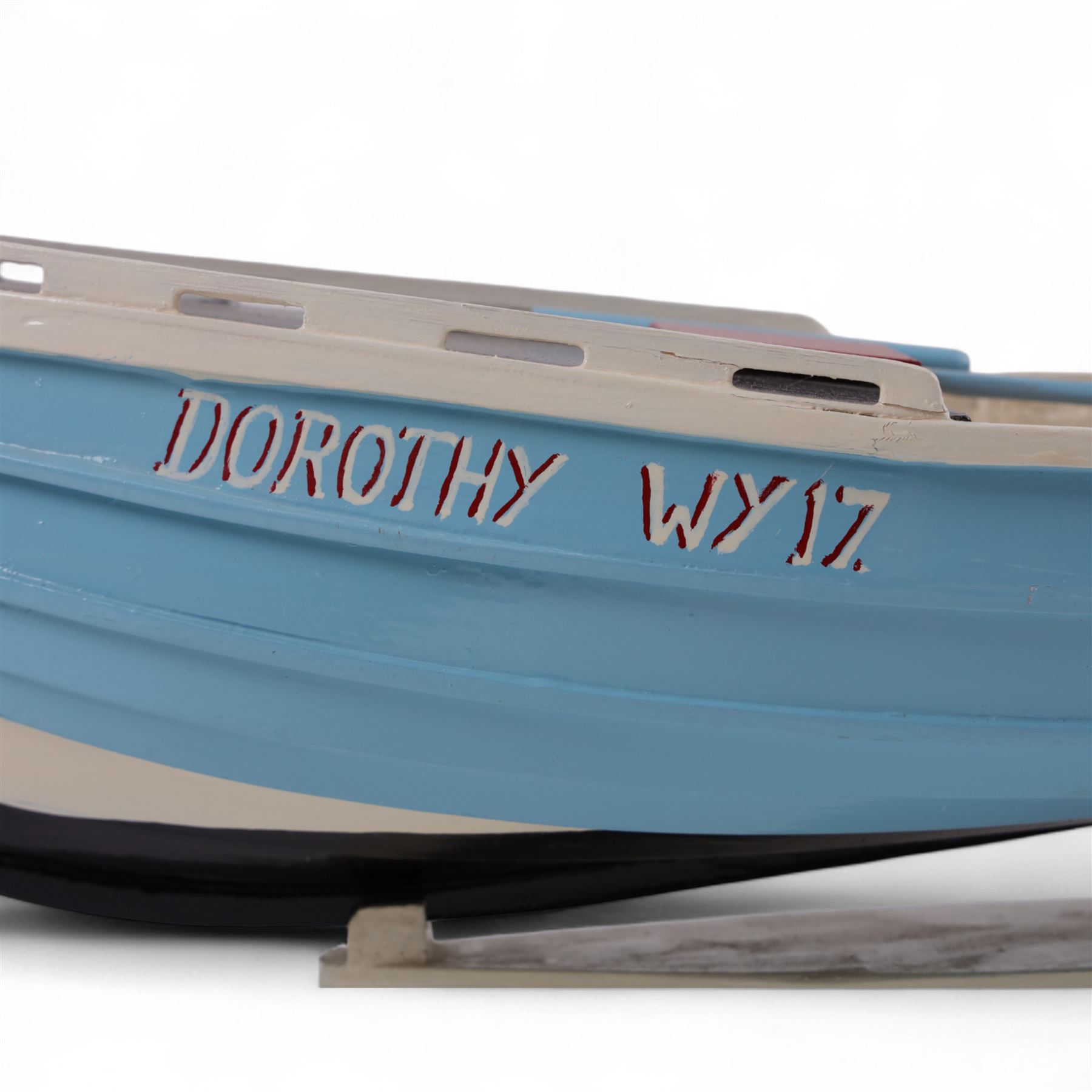 Wooden model of the Whitby fishing coble WY.17 G.Burdon 'Dorothy', painted in blue and white with red detail, with rudder and oars, on a painted wooden stand, L73cm, H20cm