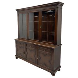 Waring and Gillow - oak bookcase on cupboard, projecting cornice over arcade frieze, guilloche upright decoration, the top section enclosed by three astragal glazed doors, the lower section enclosed by three geometric panelled doors with blind fretwork decoration, on turned feet