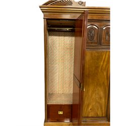 Victorian mahogany triple wardrobe, the pediment relief carved with urn and linen swags, the central panelled door carved with two fan motifs enclosing slides and drawers, two mirror glazed doors with bevelled plates enclosing hangings space and drawers, plinth base