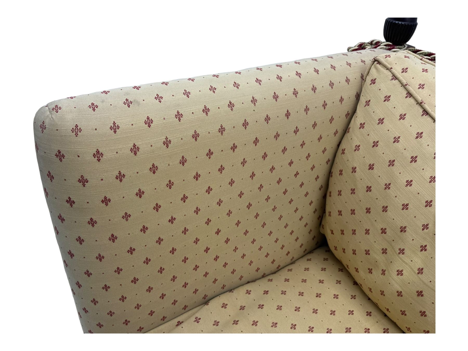 20th century Knole design two seat sofa, high back and double drop-arm joined by mahogany finials and ties, upholstered in camel ground fabric with red lozenge design, on turned supports with brass castors