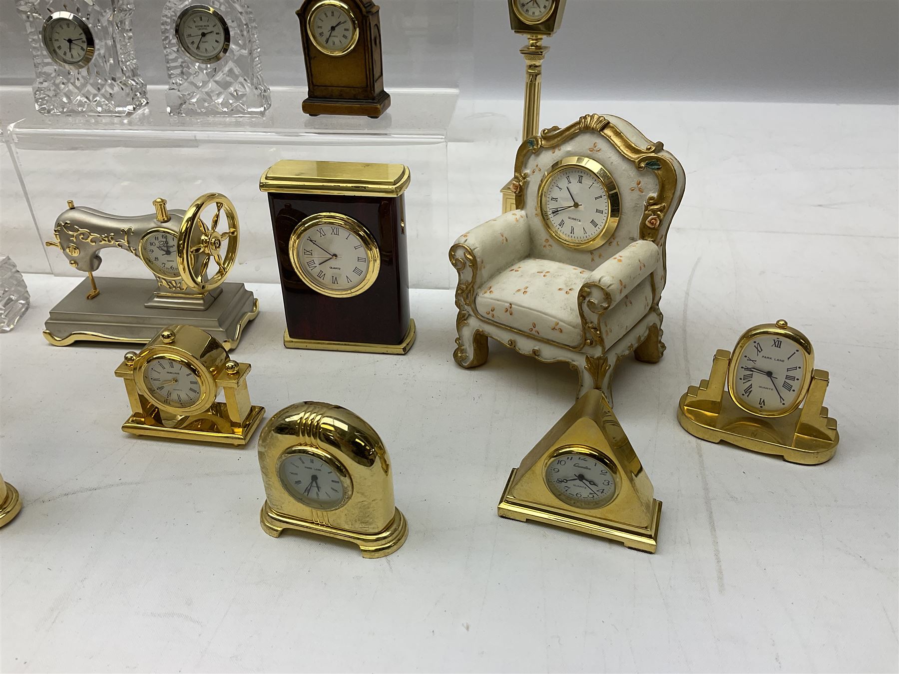 Collection of miniature clocks, predominantly with quartz movements, to include example modelled as an armchair, Edinburgh crystal glass example, clock modelled as a flower, sewing machine etc