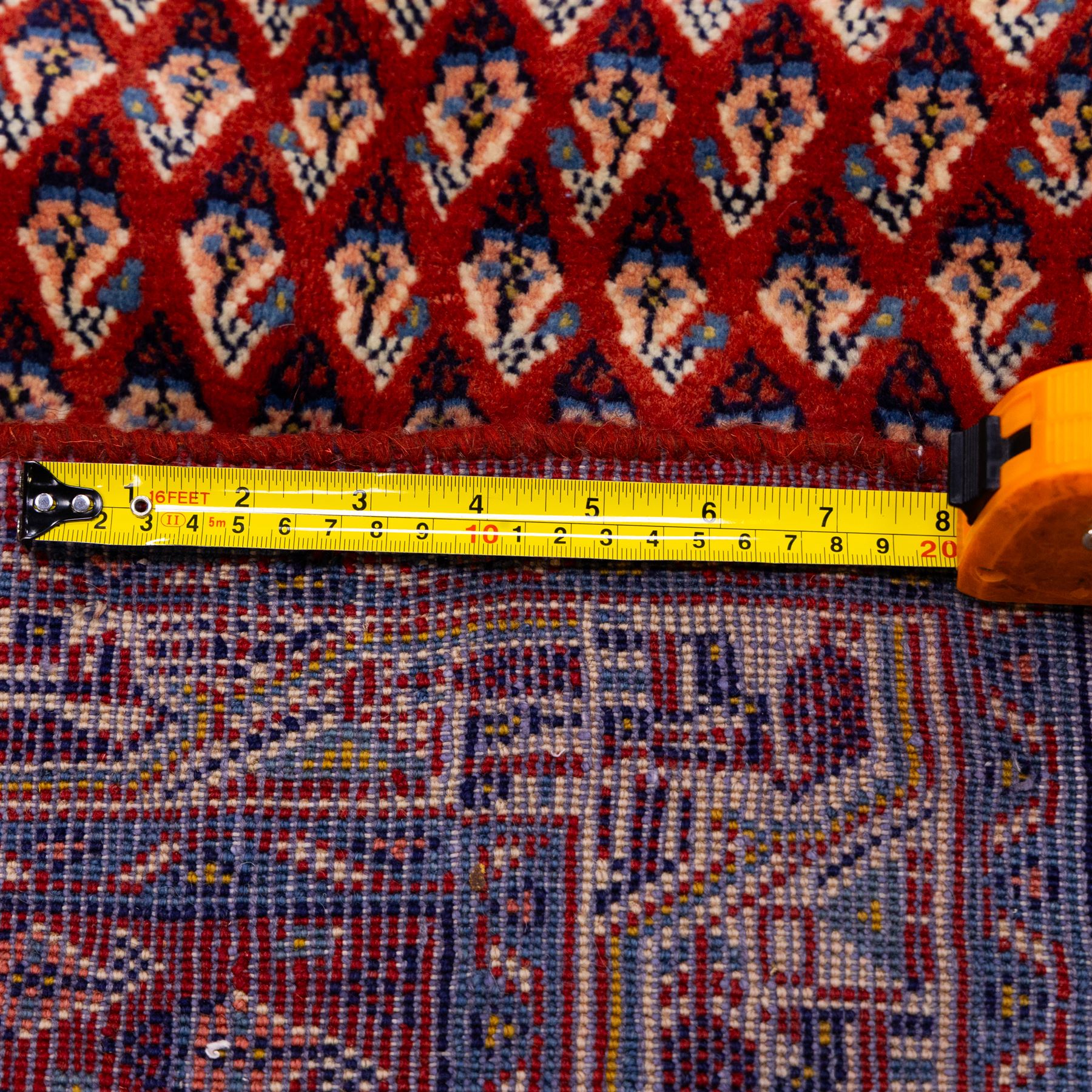 West Persian Saraband (Boteh-Mir) runner madder-red field densely decorated with repeating boteh motifs, arranged in diagonal rows enclosed by a geometric border of stylized motifs, between multiple guard stripes, cotton fringe ends  