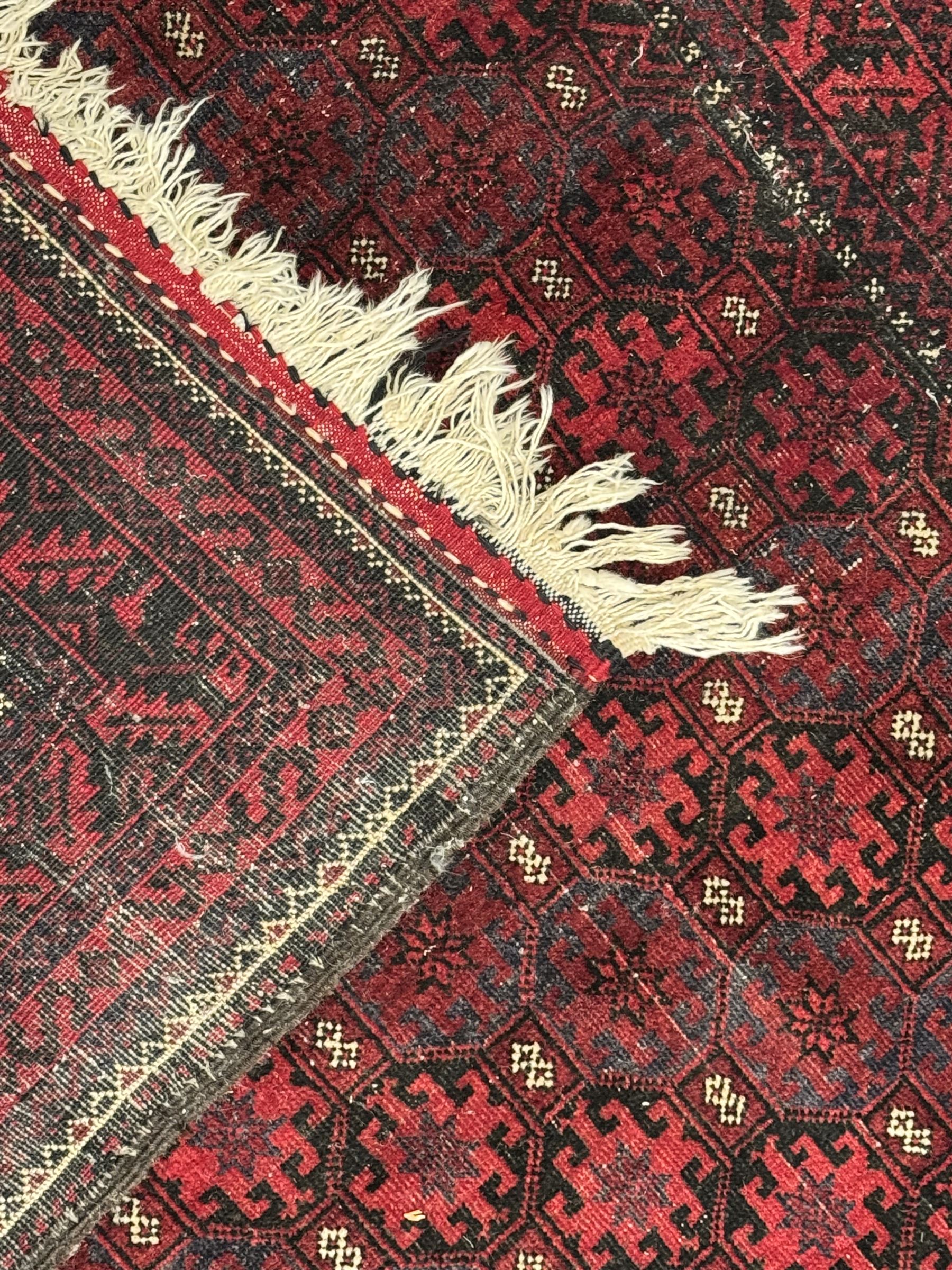 Turkoman red ground wool rug, the field with a repeating pattern of Tekke gul motifs in dark brown and red (195cm x 98cm); Afghan Bokhara red ground wool rug, central field with repeated geometric octagonal gul motifs, surrounded by multiple borders with stylised diamond and triangular patterns (127cm x 181cm)