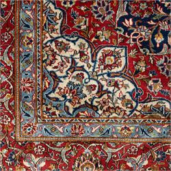 Persian Kashan carpet, navy field with central red diamond medallion enclosing floral rosette, framed by dense scrolling foliage and palmettes, triple borders in red, blue and ivory, originating from central Iran