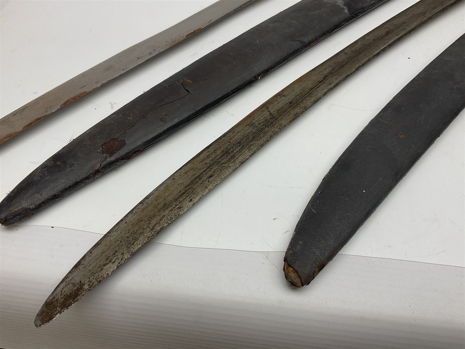 Four Indian tulwar swords; three with cast brass hilts and one with iron hilt; longest blade 81cm; all with scabbards (4)