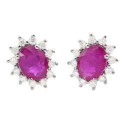 Pair of 18ct white gold ruby and diamond cluster earrings, each stud set with a single ova...