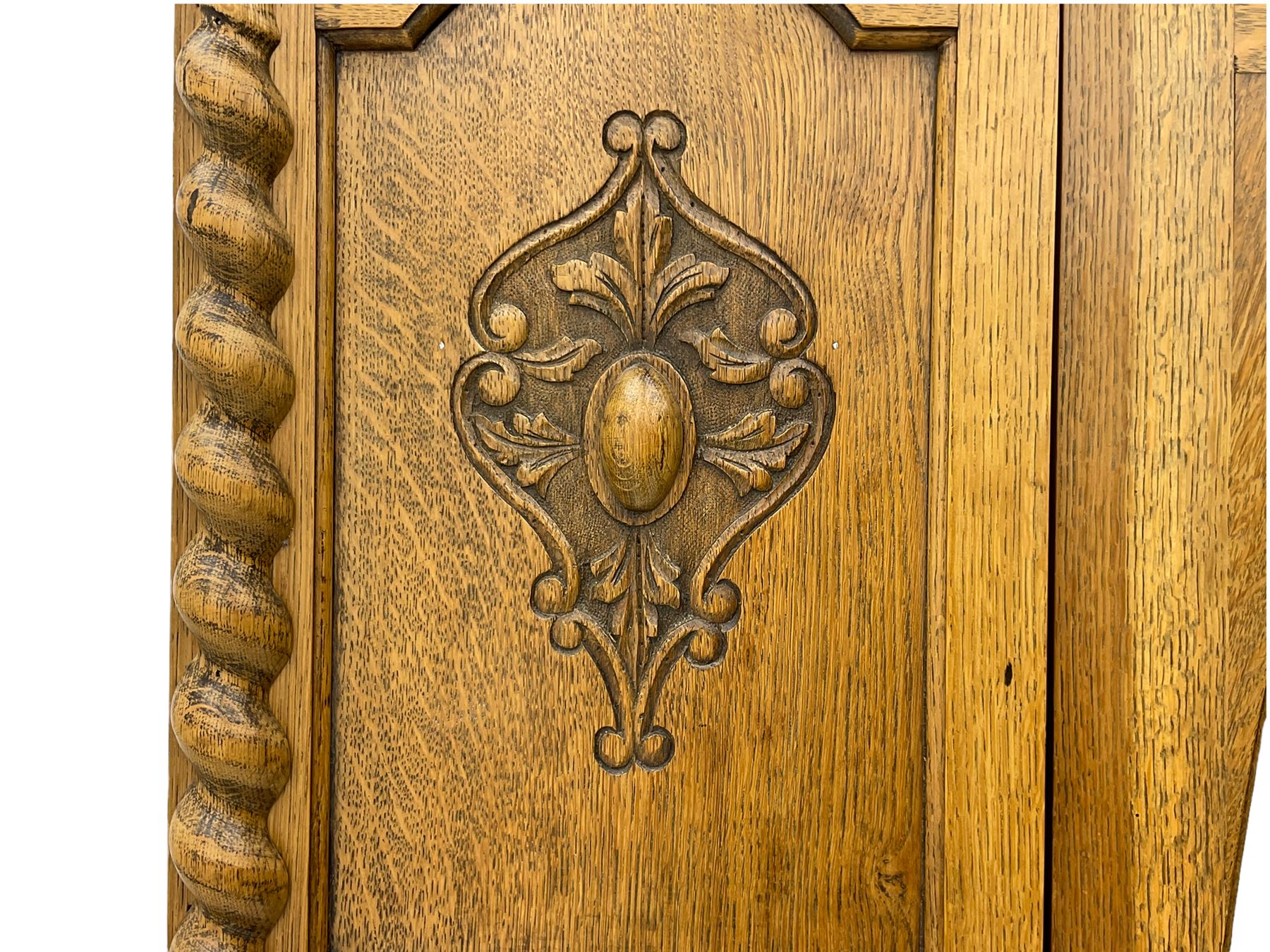 Early 20th century oak wardrobe, projecting cornice of blind fret-work frieze, oval bevel edge mirror door, half spiral turned pilasters, drawer to base with mouldings, on turned bun feet