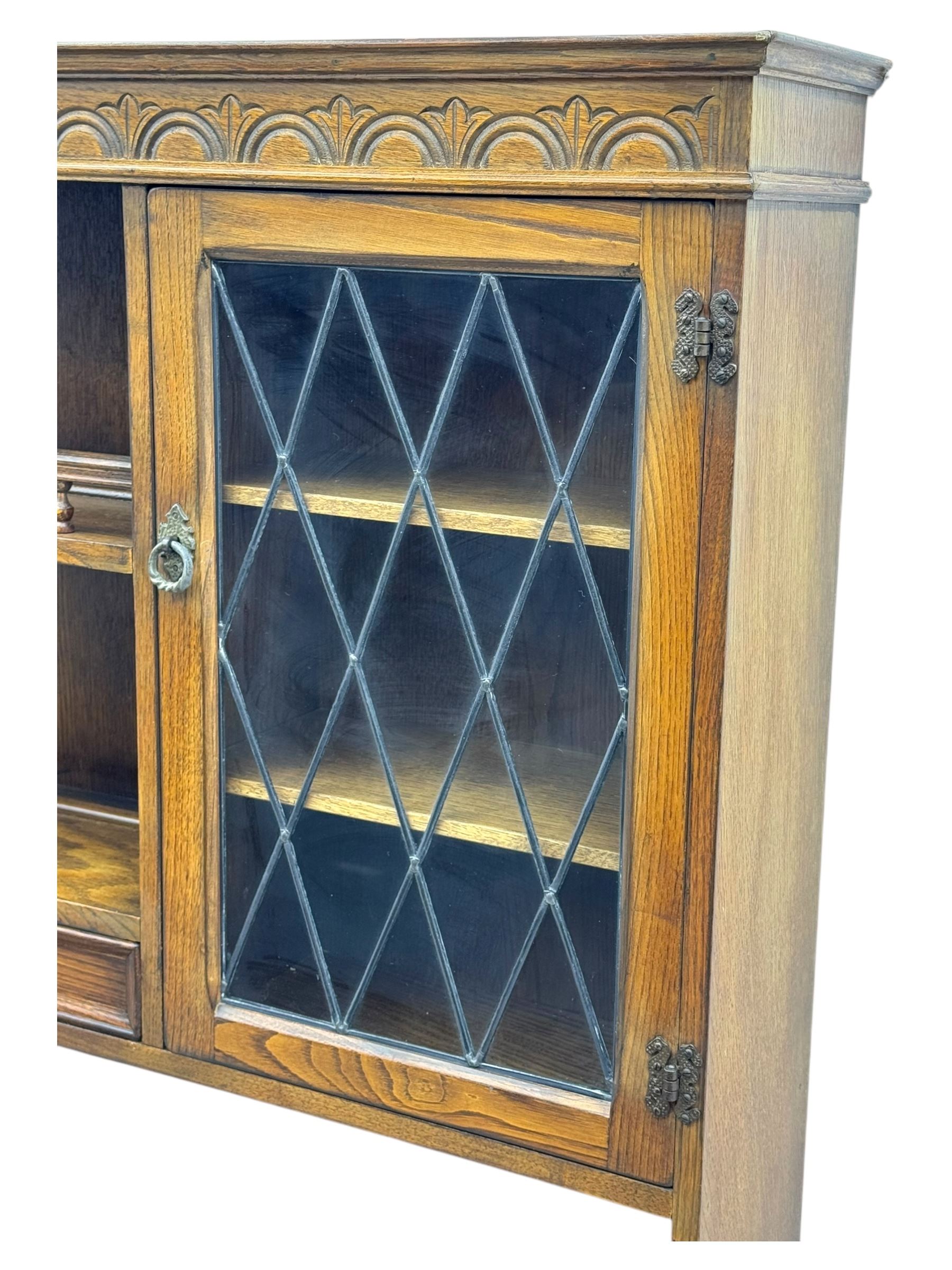 Large mid-20th-century oak dresser with two astragal glazed doors between gallery shelf and lower shelf, with three short drawers and lower section with four drawers and three double-panelled linen-fold hinged cupboard doors 