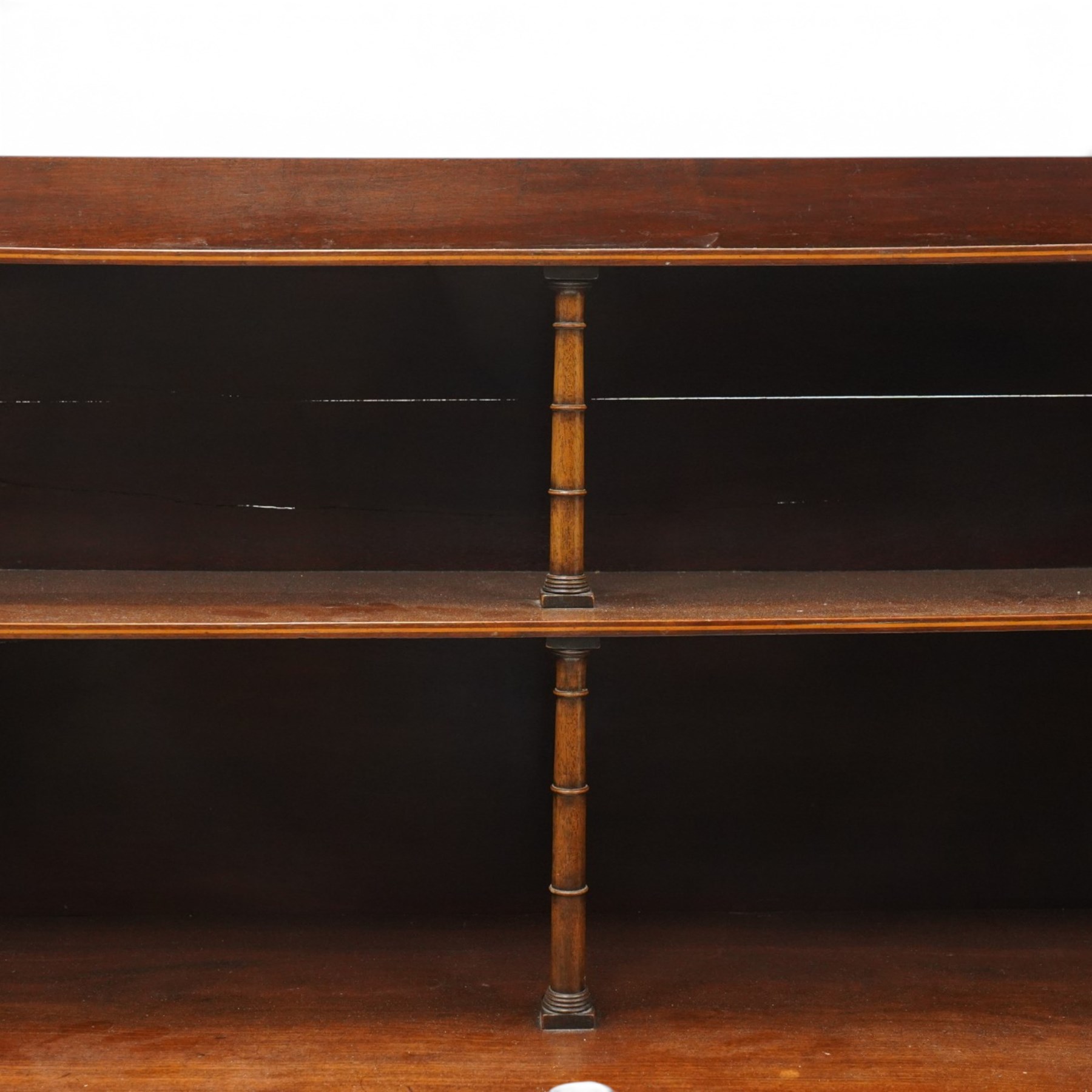 Regency period mahogany waterfall-bookcase chiffonier, the raised back with two open shelves supported by central ring-turned pilasters, fitted with twin doors with sage-green pleated fabric facias, over two drawers with satinwood stringing, raised on front sabre supports