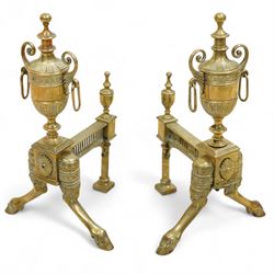 19th century brass and iron fire dogs with fire irons, the fire dogs each with urn finials and arched legs, accompanied by three brass fire tools including shovel, poker and tongs with matching turned handles