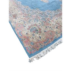 Large Persian design carpet, plain light blue field with floral design central medallion, scrolling foliate spandrels and borders decorated with flower heads