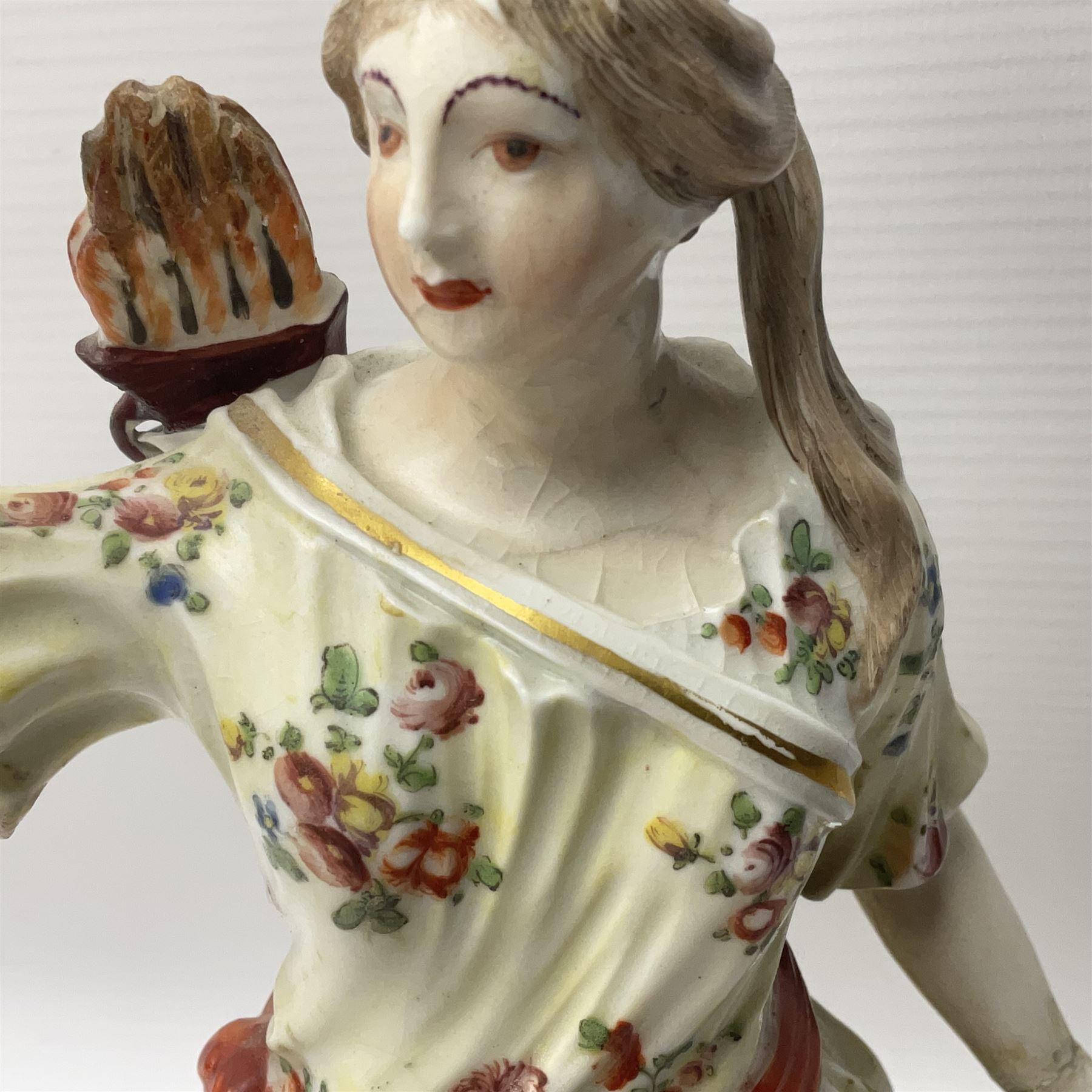 18th century Derby figure of Diana the huntress, circa 1760, modelled reaching for an arrow from quiver across her back, with recumbent hound at her feet, upon a scrolled base with bocage detail, H27.5cm