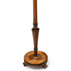 20th century walnut standard lamp, flared and faceted column over circular stepped base with shaped feet, with later scalloped cream fabric shade and fringe trim