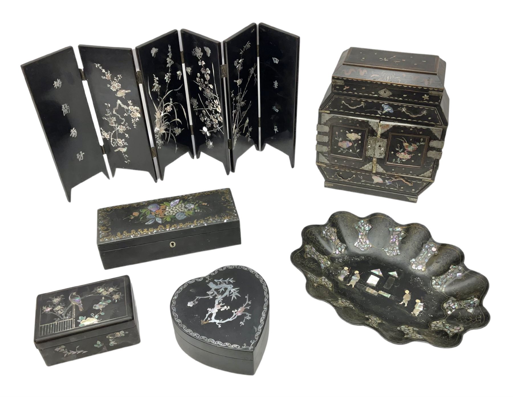  Late 19th / early 20th century Japanese lacquered table top cabinet, heavily decorated with mother of pearl inlay depicting blossoming branches, flowers and birds, the two hinged doors between longer drawers opening to reveal interior fitted with four short drawers, with lift up hinged canted lid, H28cm D9.5cm W23cm, together with mother of pearl inlaid miniature folding screen, dish decorated with walking figures with crimped edge, boxes decorated with flowers, birds and gilt etc