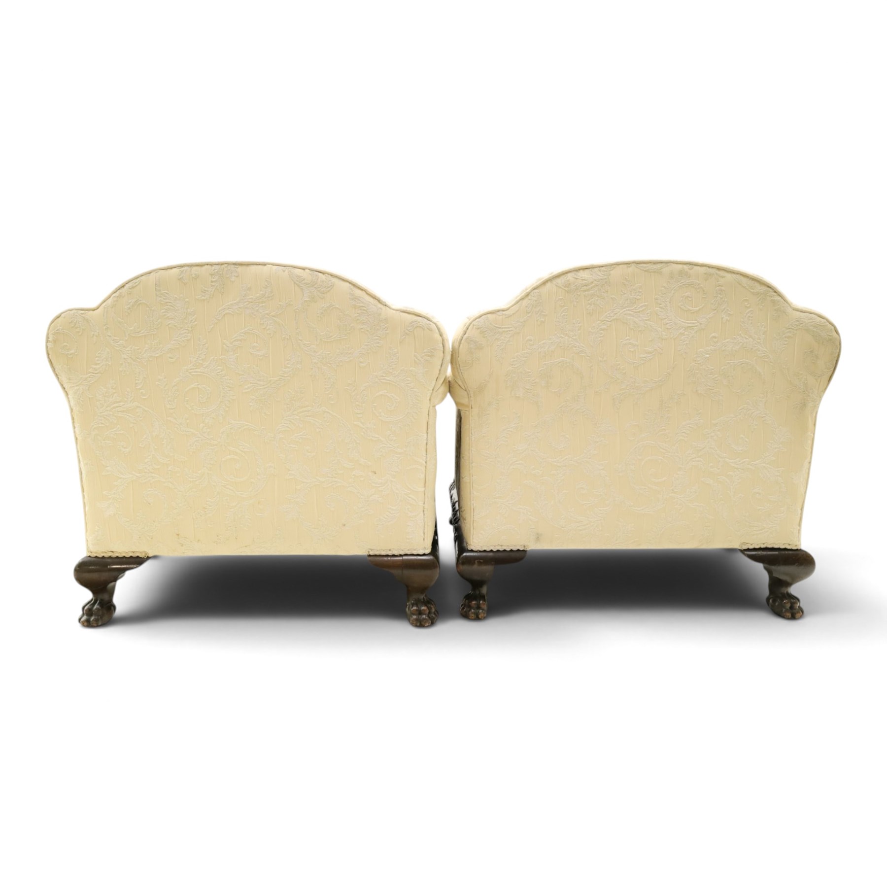 Quality Edwardian carved mahogany lounge suite comprising three-seater settee and pair of armchairs, the sofa with arched back over rolled arms and deep sprung seat, the arm terminals carved with acanthus rosette over gadroon and rope-twist moulding, the shaped apron carved and moulded with scrolling foliate acanthus motifs, terminating to four large front hairy paw and ball feet, upholstered in pale yellow foliate fabric with matching seat and scatter cushions (W200cm D105cm H73cm); the matching deep armchairs (W78cm D95cm H75cm)