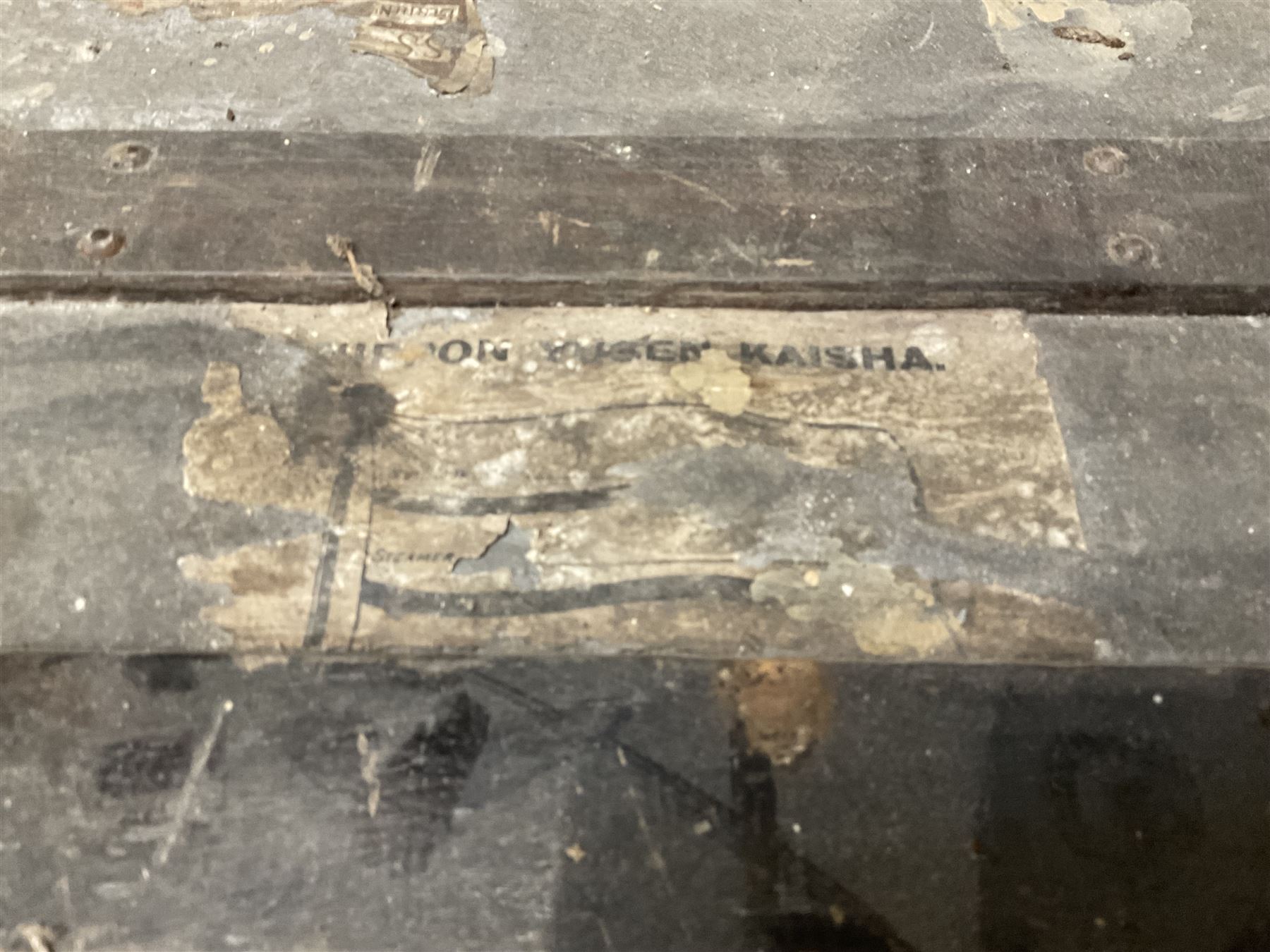 Early 20th century wood and metal bound zinc travelling trunk, hinged top with three clasps, decorated with period luggage labels