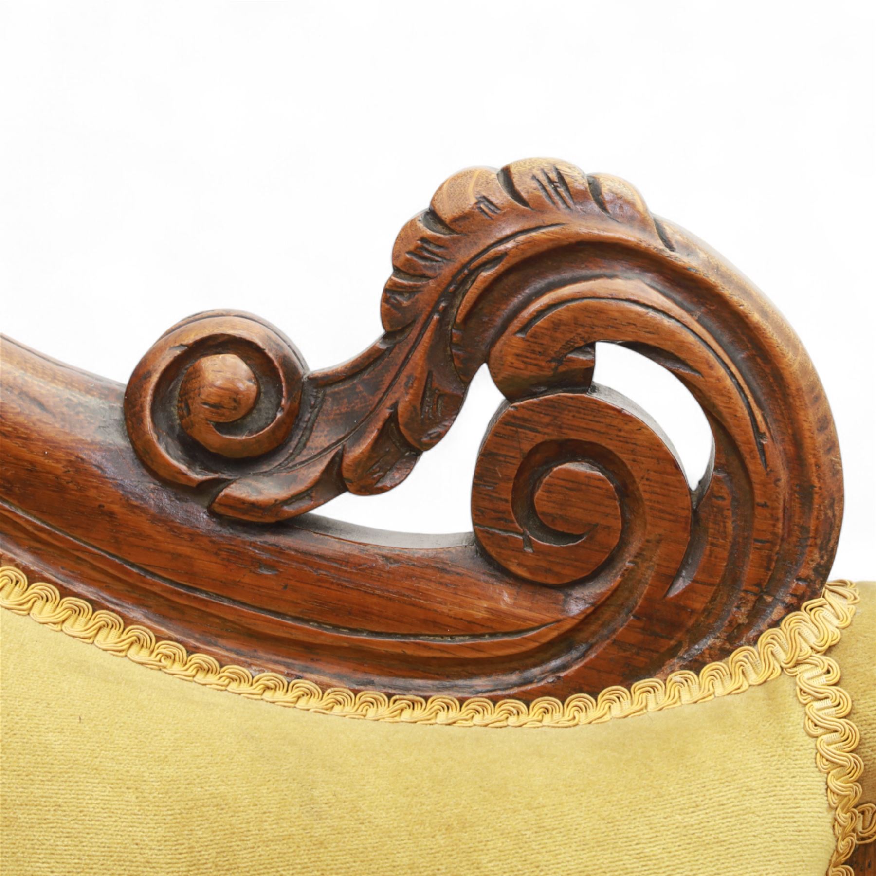 Victorian walnut chaise longue, carved with scrolling acanthus to the end supports and seat rail, upholstered in mustard coloured velvet, shaped and buttoned back and side with turned spindle gallery, raised on short turned legs with ceramic castors 