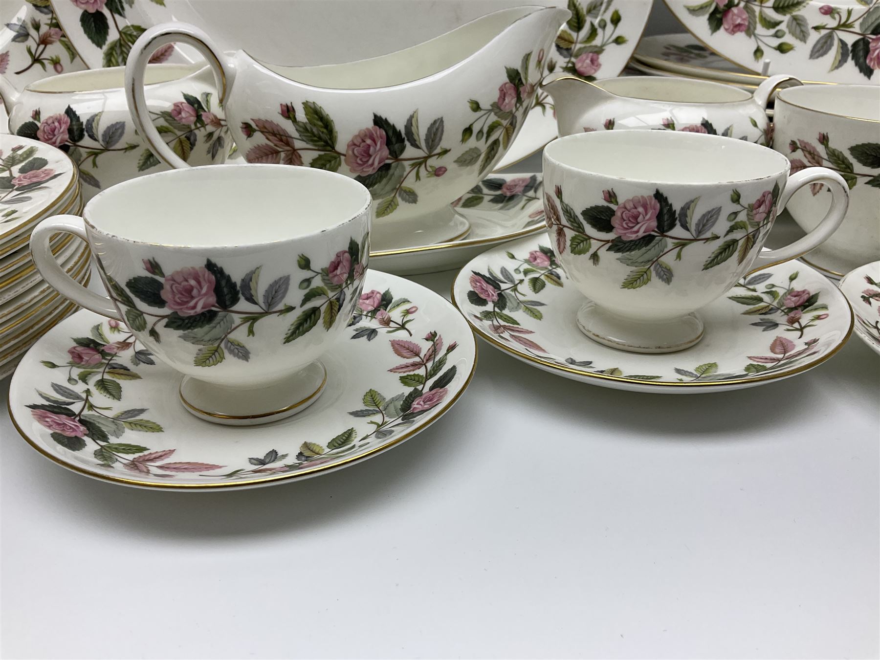 Wedgwood Hathaway Rose pattern tea and dinner wares, comprising twelve saucers, sixteen teacups, twenty tea plates, jug, sucrier, thirteen shallow bowls, sauce boat and saucer, two lidded tureens, larger jug, ten dinner plates, nine smaller plates and two large oval serving dishes