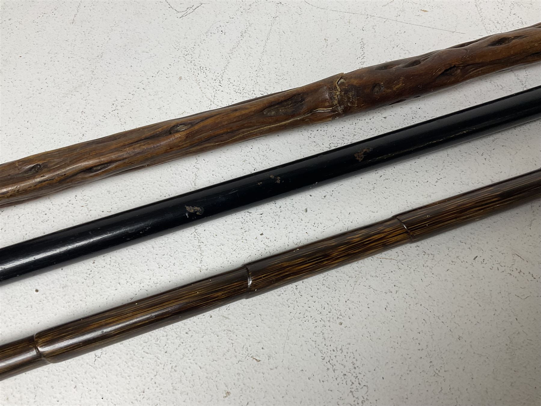 19th century painted bamboo walking cane, the handle carved as a fox with glass eyes, with gilt metal stamped LB, together with an ebonised wooden walking stick, with horn pommel and hallmarked silver collar and a curved wooden walking stick, with monogrammed white metal cap, tallest L90cm