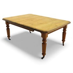 Early 20th century stripped pine kitchen table, the rectangular planked top with moulded edge and canted corners, upon stained pine turned and fluted legs with castors