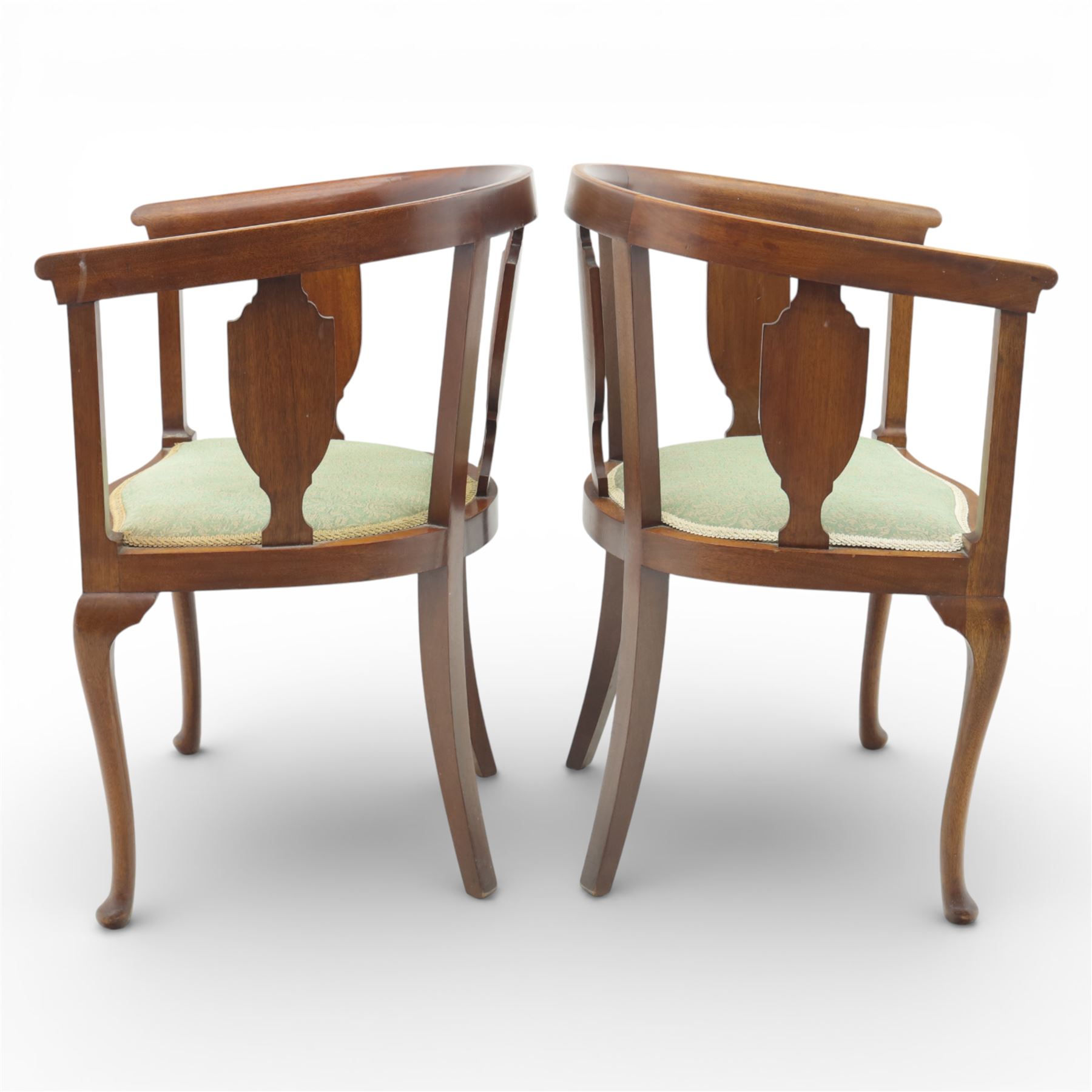 20th century mahogany tub chairs, the arched backs enclosing shaped splat panels and plain uprights, open curved arms flowing into the seat rails, upholstered seats in green foliate patterned fabric, on cabriole legs