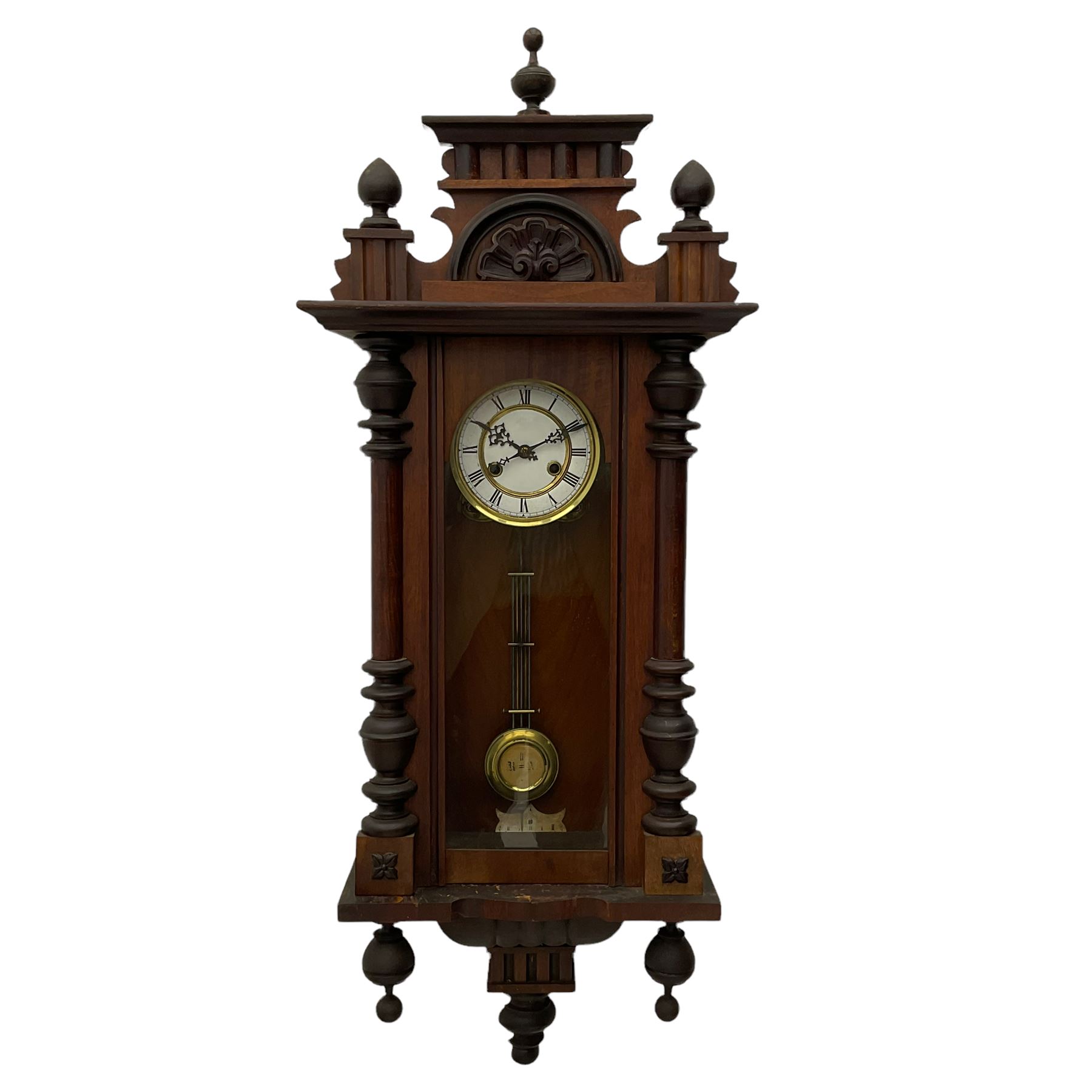 A late 19th century German wall clock with an 8-day spring driven movement striking the hours on a coiled gong, in a mahogany case with a shaped pediment and turned columns flanking a full-length glazed door, with a two-part dial enamel with Roman numerals, minute track and pierced gothic designed hands, gridiron pendulum and beat plate. With Key.




