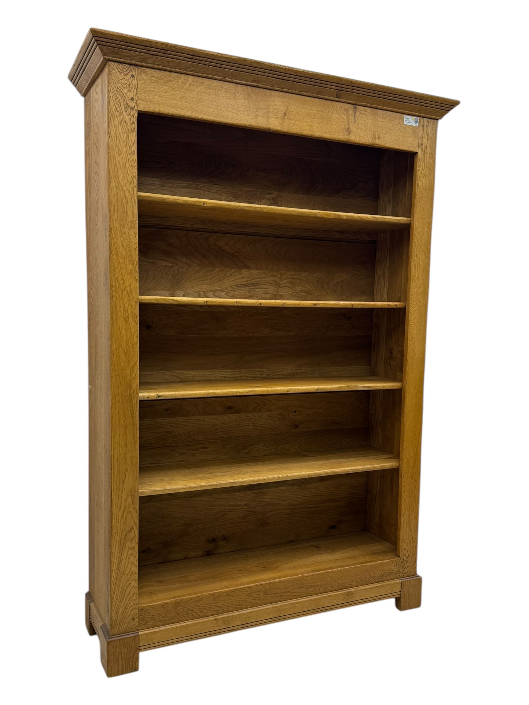 Contemporary French provincial design oak open bookcase, with projecting moulded cornice above a boarded back, fitted with four adjustable shelves, on bracketed plinth base