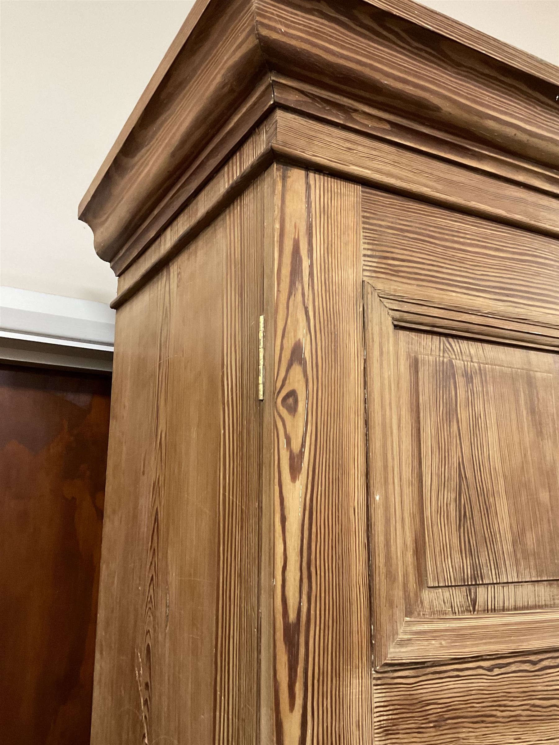 Victorian pitch pine double wardrobe, projecting moulded cornice over two panelled doors, the interior fitted with hanging rail and hooks, single drawer to base