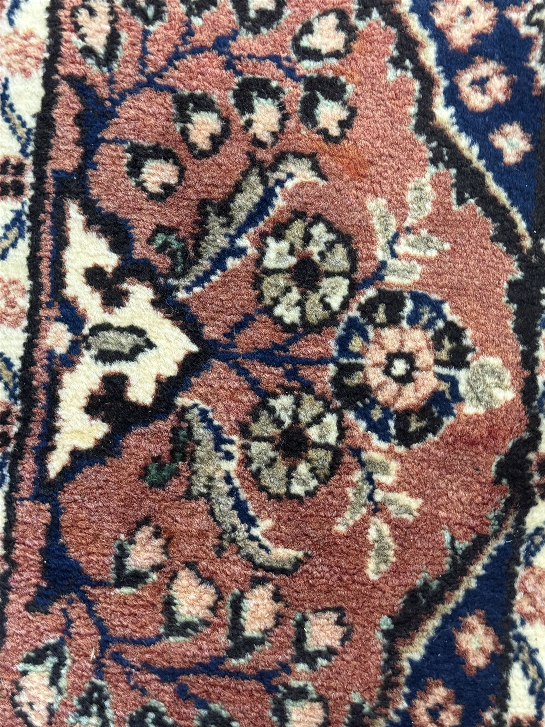 Persian Herati design indigo and red ground carpet, decorated with floral motifs, arched border