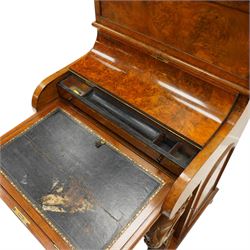Victorian burr walnut piano-top Davenport, the raised rectangular superstructure with moulded cornice above a panelled fall-front enclosing drawers, the curved hinged writing slope opening to reveal a fitted interior above a sliding tooled leather writing surface, flanked by carved foliate scroll supports, the right side fitted with four drawers behind an arched panelled cupboard door with brass inset campaign-style handles, on a shaped plinth base and bun feet