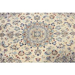 Central Persian Nain hand-knotted silk and wool rug, ivory field with a cusped medallion  issuing radiating pendants, with an all-over design of scrolling arabesques, palmettes and floral sprays, framed main border of meandering vinery and stylized palmettes, flanked by narrow guard stripes, cotton fringe ends  