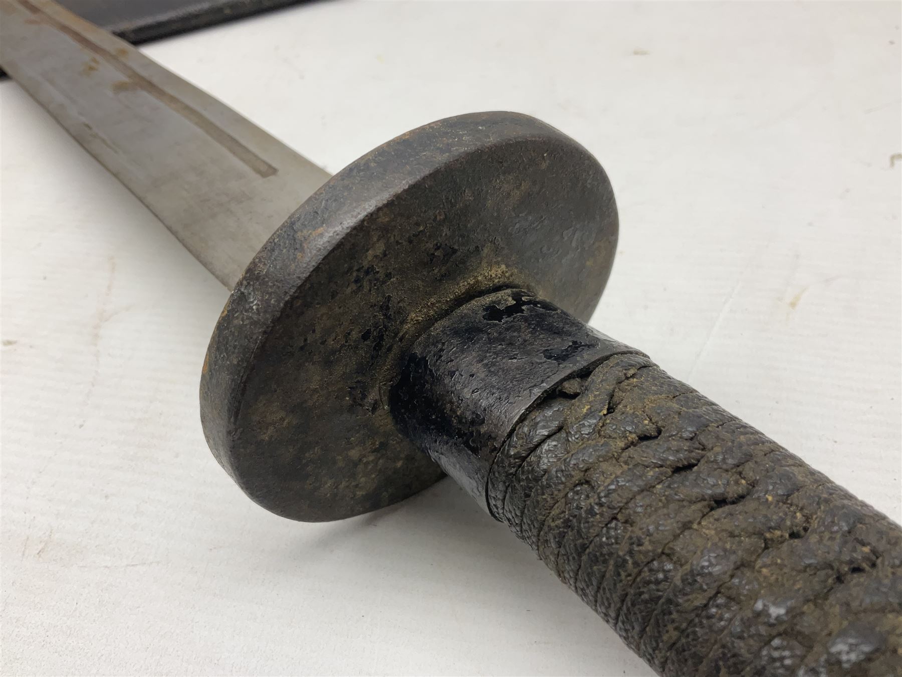 Chinese Boxer Rebellion Period Sword, 69.5cm heavy curved single edge blade with single narrow fuller, plain iron dished circular guard, iron pommel and ferrule with plaited cord bound grip; in skin covered wooden scabbard with iron chape and long suspension mount L95cm overall