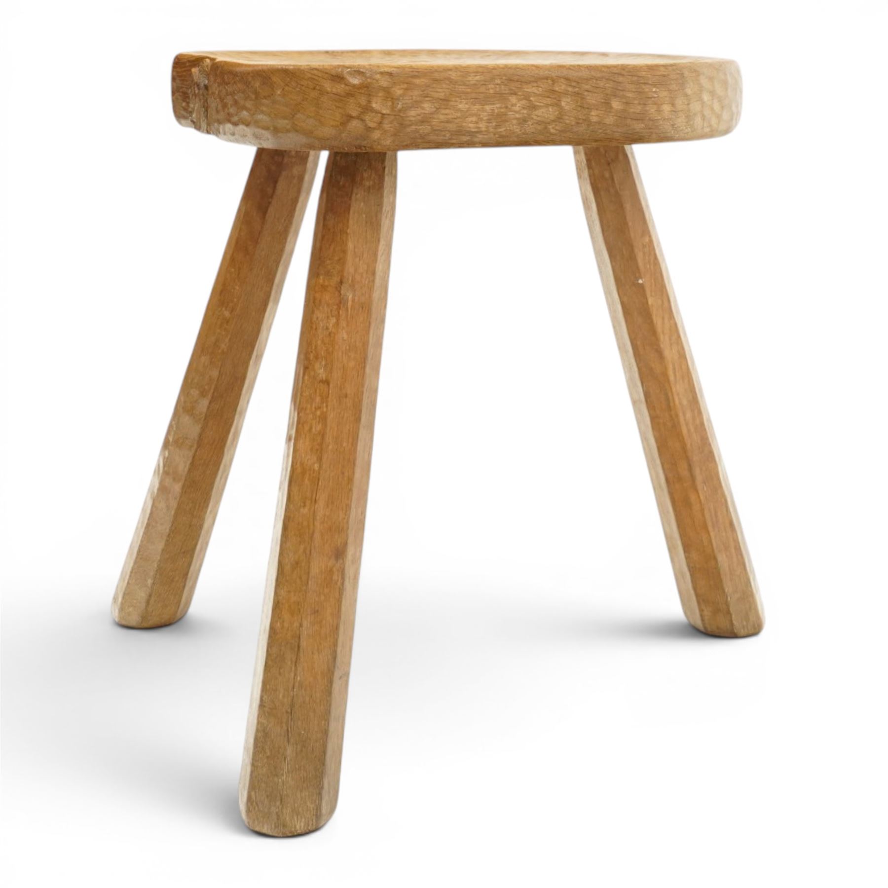 Squirrelman - rustic oak milking stool, adzed shaped top with exposed peg construction, on three tapering supports, with large carved squirrel signature, by Wilf Hutchinson, Husthwaite