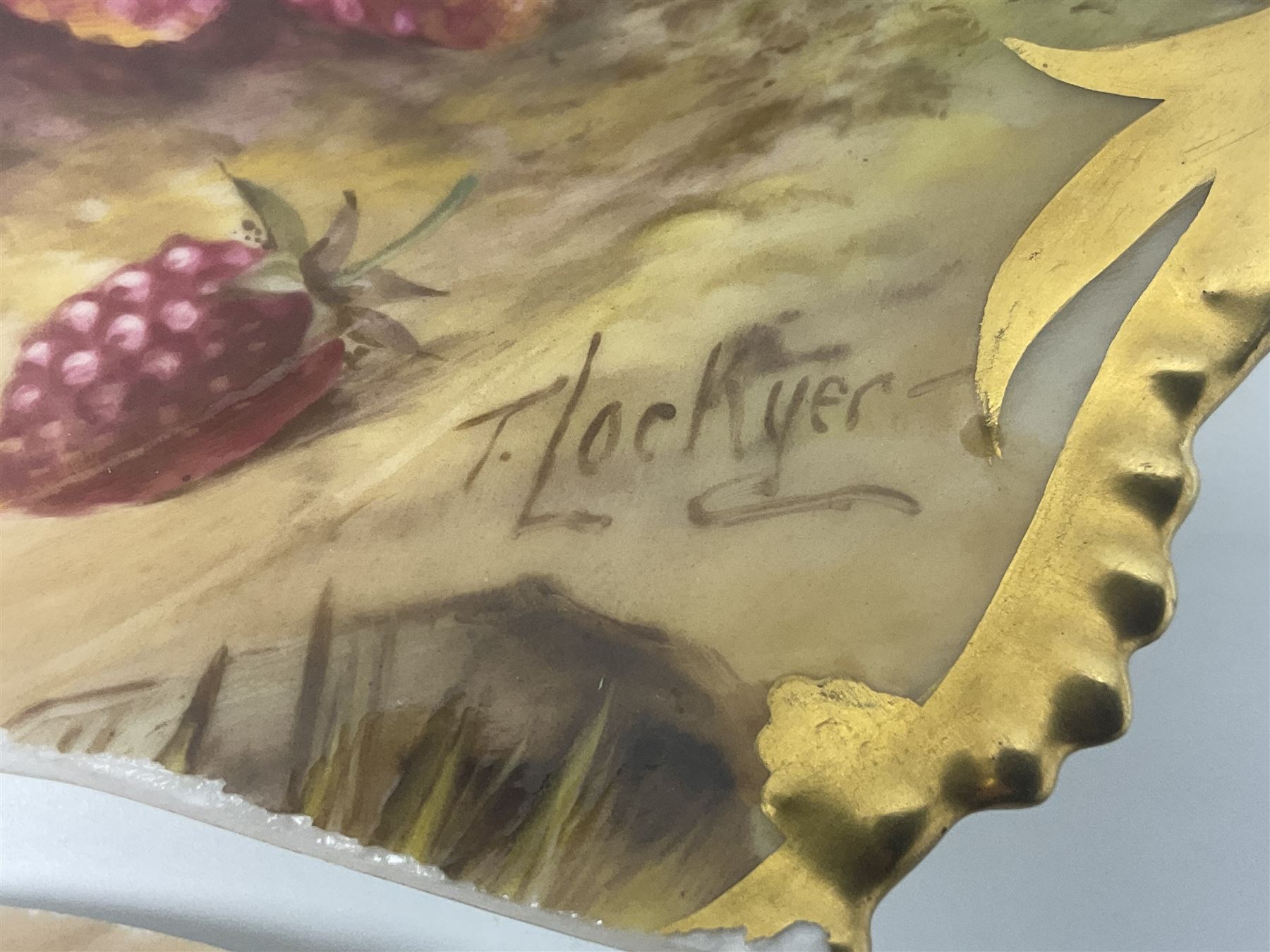 Early 20th century Royal Worcester dish decorated by Thomas Lockyer, oval form with gilt shaped rim and twin shell handles, hand painted with a still life of fruit upon a mossy ground, signed T Lockyer, with puce printed mark beneath and date code for 1922, for restoration, W31cm